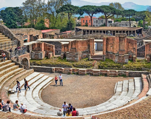 Visitors exploring the ancient ruins of the Pompeii Amphitheater in Italy.