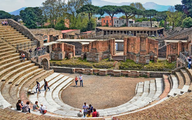 Visitors exploring the ancient ruins of the Pompeii Amphitheater in Italy.