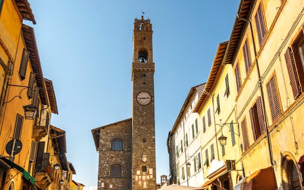 Clock tower in Montepulciano, Tuscany, surrounded by historic buildings.