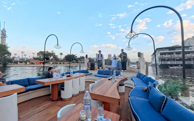 Nile Dahabiya dinner cruise with guests seated on deck, Cairo Tower in background.