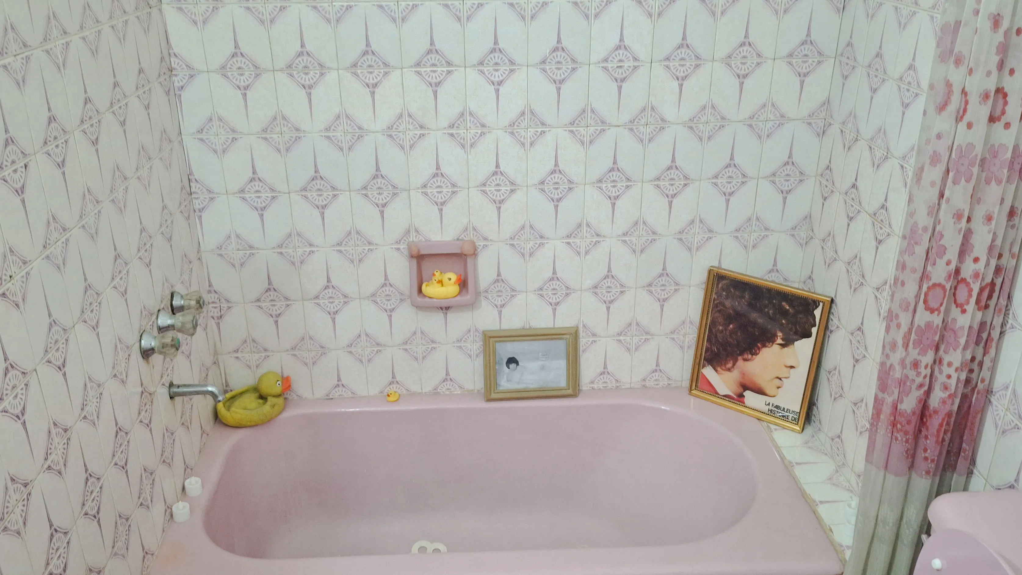 Pink bathtub with rubber ducks and framed photos, part of Maradona Walking Tour in Buenos Aires.