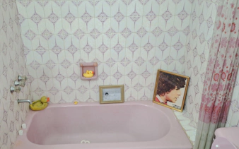 Pink bathtub with rubber ducks and framed photos, part of Maradona Walking Tour in Buenos Aires.