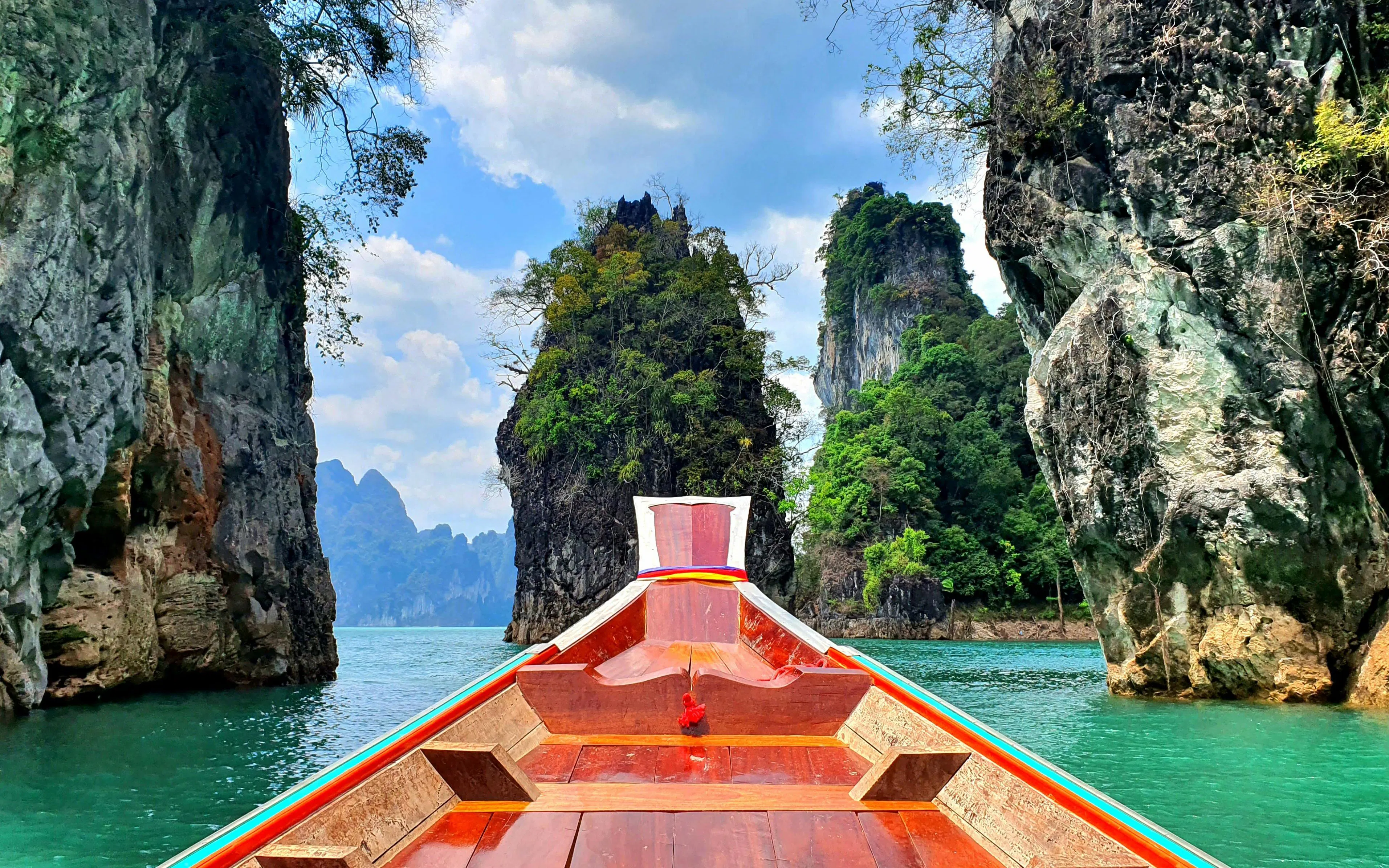 Boat navigating between limestone cliffs on Cheow Lan Lake, Krabi.
