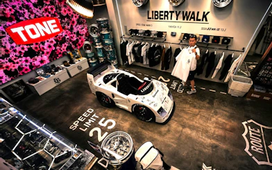 Liberty Walk showroom in Tokyo featuring JDM car model and merchandise display.