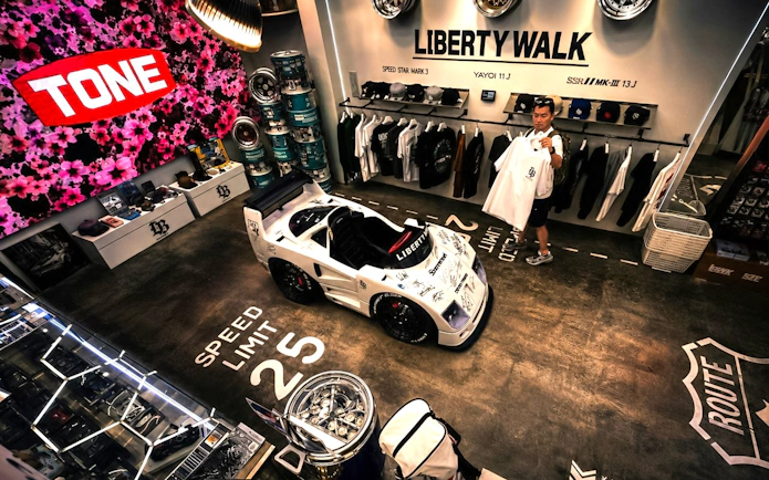 Liberty Walk showroom in Tokyo featuring JDM car model and merchandise display.