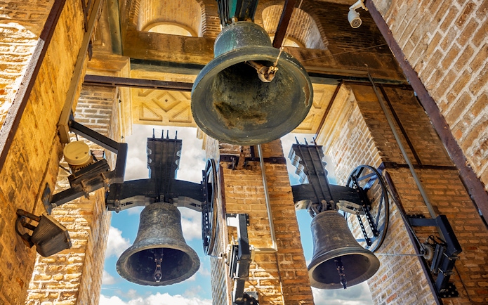 Bells of the Giralda tower in Seville, Spain against a blue sky.