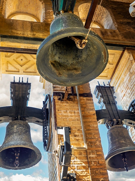 Bells of the Giralda tower in Seville, Spain against a blue sky.