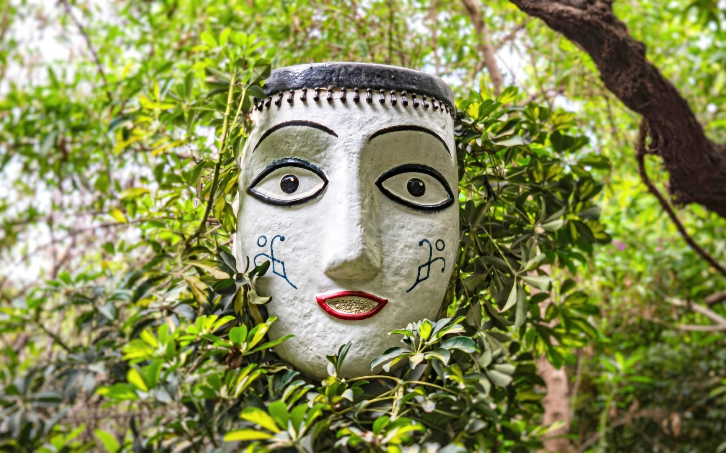 Sculpted face surrounded by greenery at Anima Garden near Marrakech, Morocco.