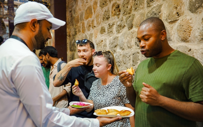 Visitors enjoying street food tasting experience.