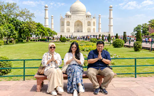 Visitors sitting in front of the Taj Mahal during a private sunrise day trip in Agra.