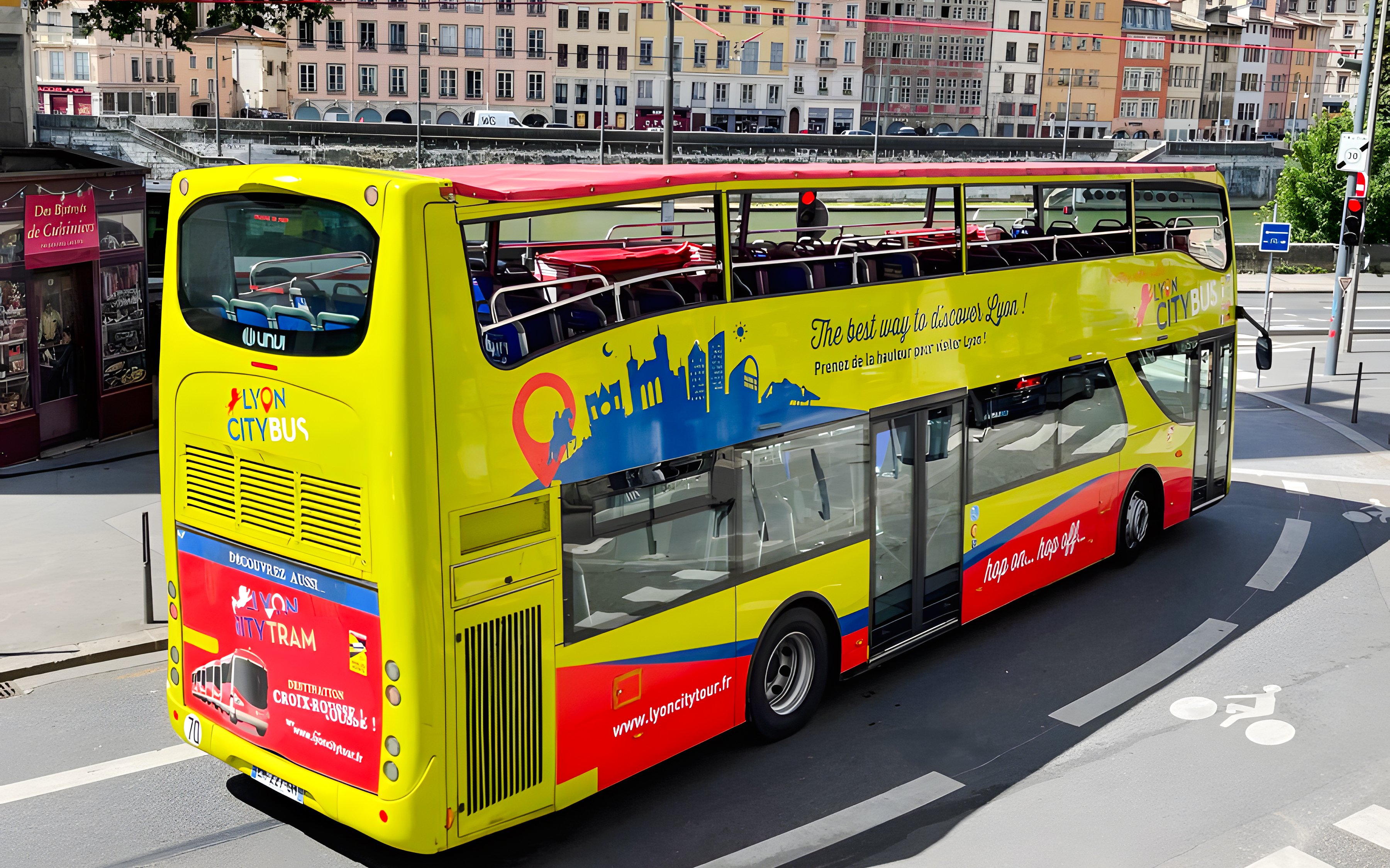 Open-top yellow Lyon city tour bus on a street in France.