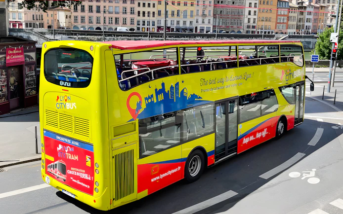 Open-top yellow Lyon city tour bus on a street in France.
