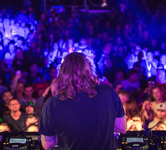 DJ performing with headphones at a vibrant nightclub party.