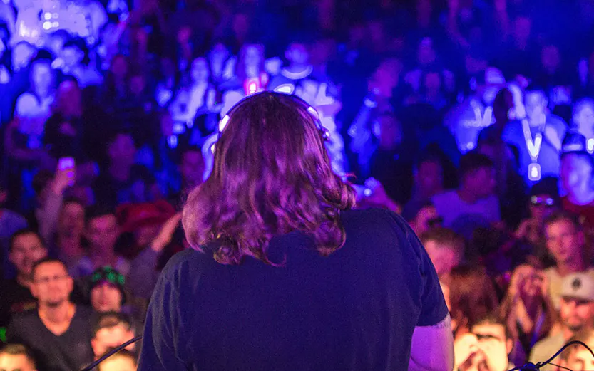 DJ performing with headphones at a vibrant nightclub party.