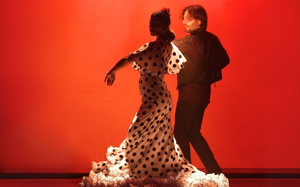 Flamenco dancers performing in Barcelona against a red backdrop.