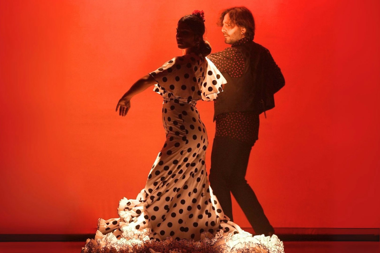 Flamenco dancers performing in Barcelona against a red backdrop.