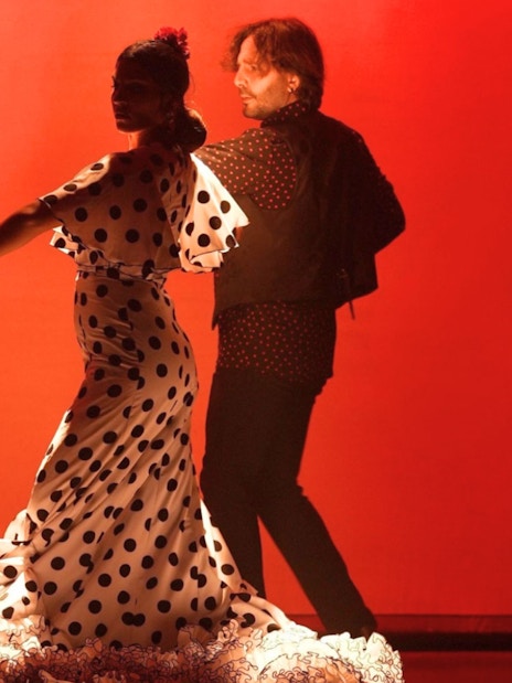 Flamenco dancers performing in Barcelona against a red backdrop.