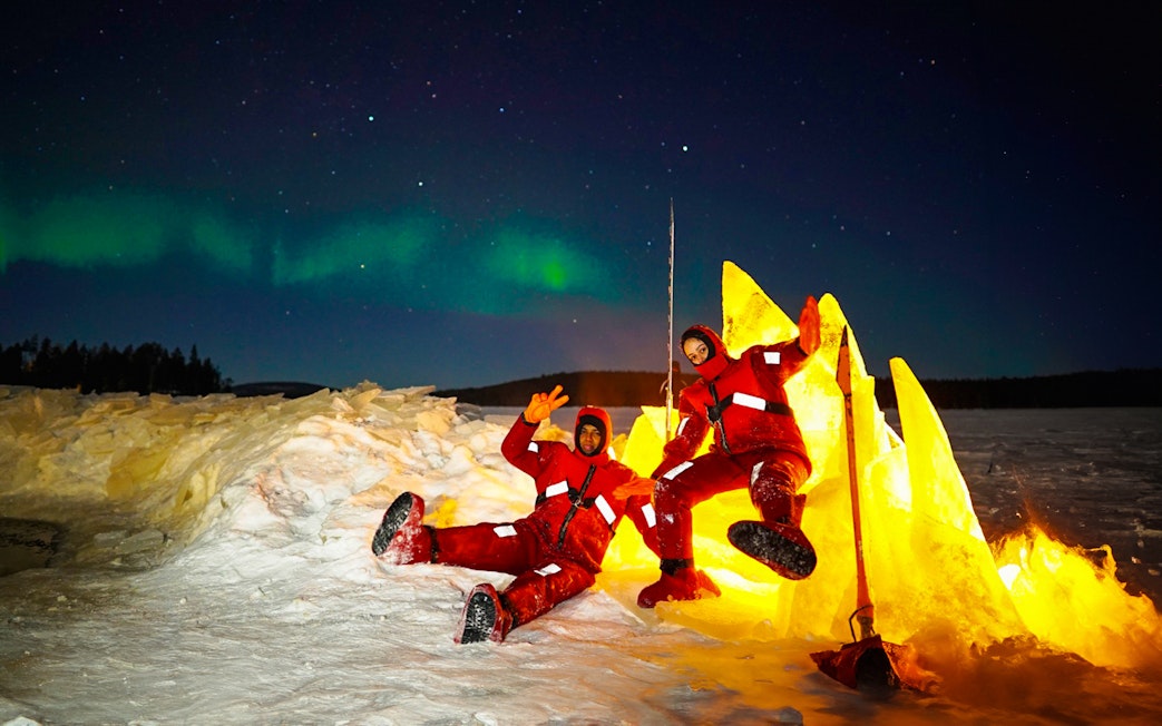 Two people in red suits enjoying Northern Lights ice floating experience.
