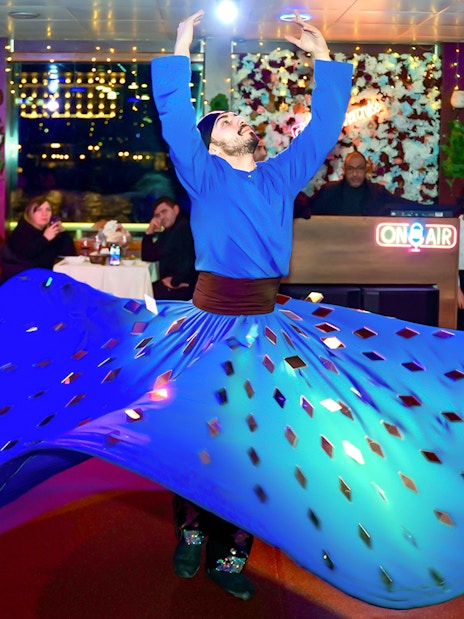 Dervish dancer performing on Bosphorus Dinner Cruise with audience watching.