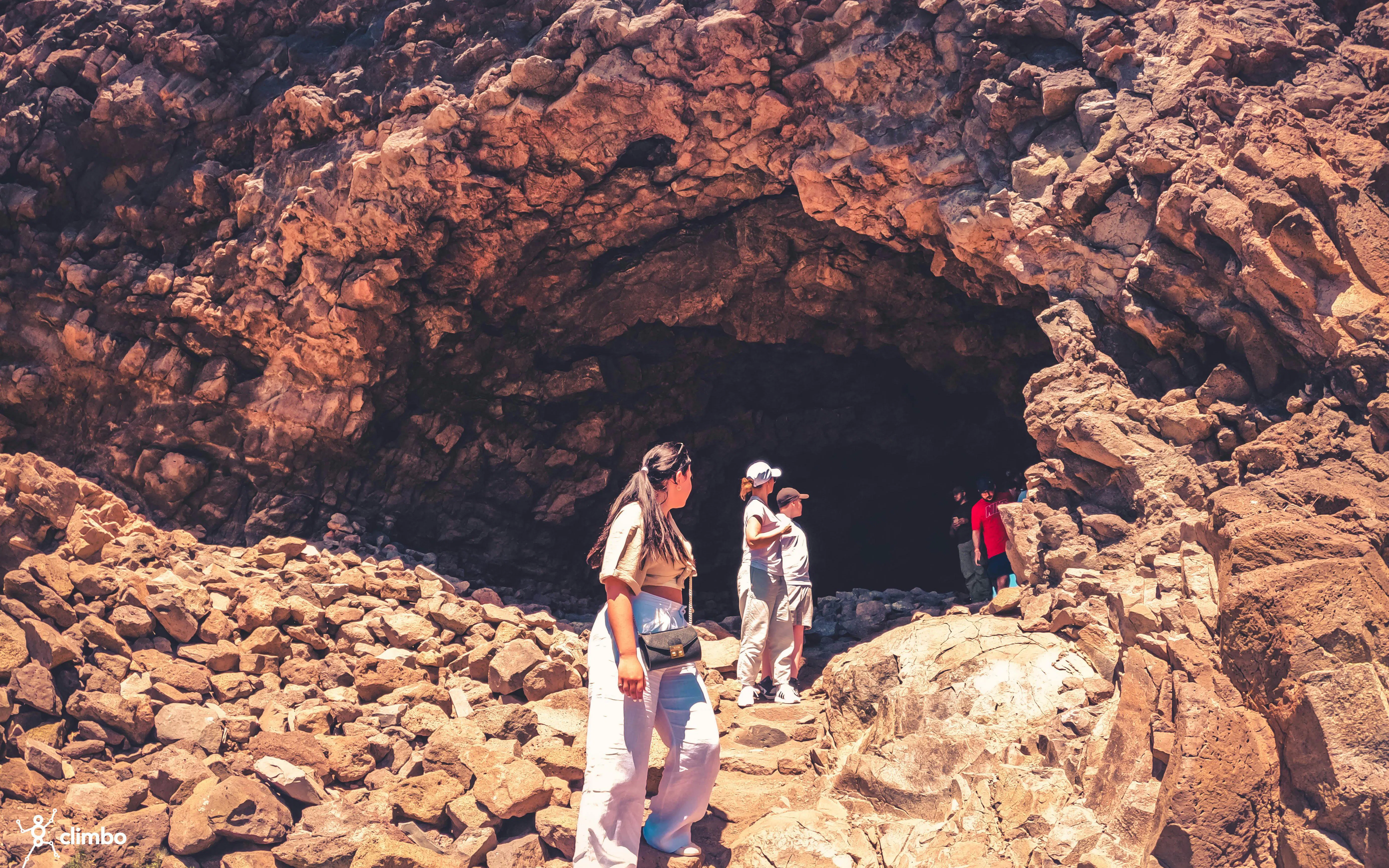 Visitors exploring rocky cave entrance on Red Canyon Tour, Gran Canaria.