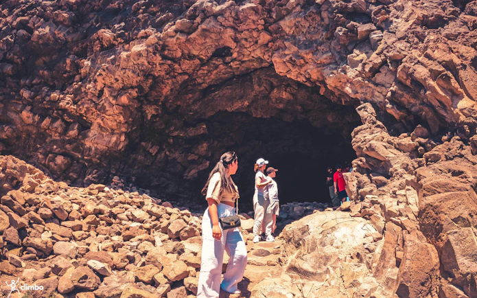 Visitors exploring rocky cave entrance on Red Canyon Tour, Gran Canaria.