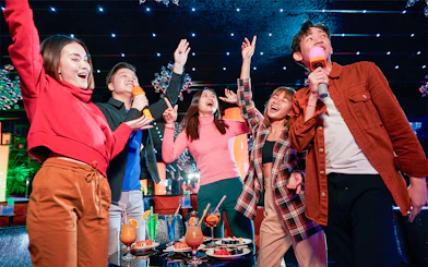 Group enjoying karaoke and drinks at a vibrant indoor venue in Singapore.