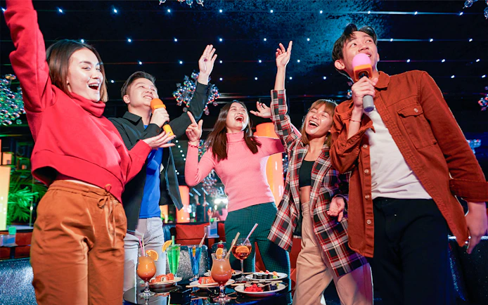 Group enjoying karaoke and drinks at a vibrant indoor venue in Singapore.