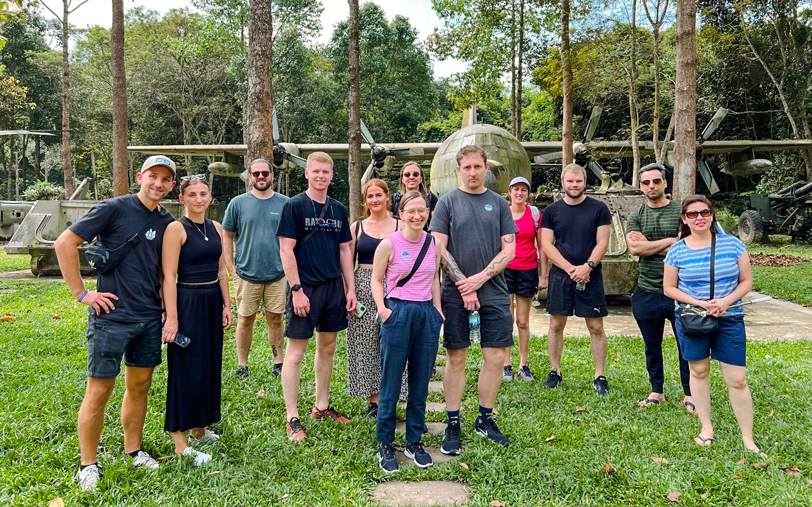 Tour group standing in front of military aircraft at Cu Chi tunnels, Vietnam.