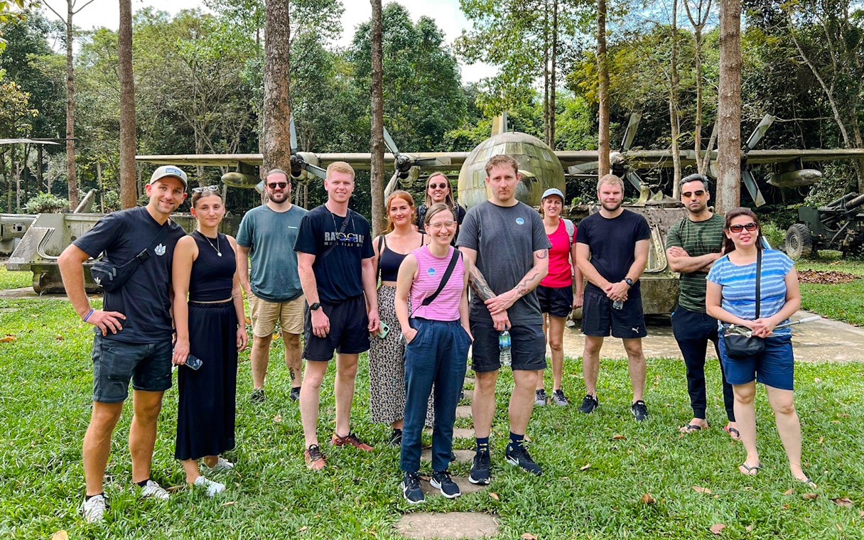 Tour group standing in front of military aircraft at Cu Chi tunnels, Vietnam.