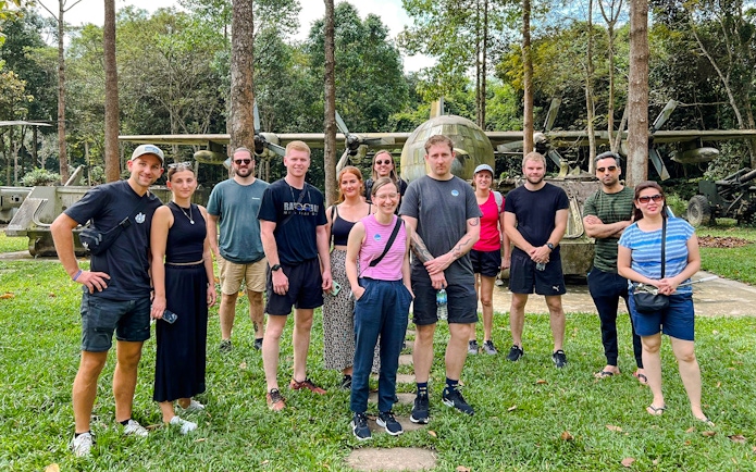 Tour group standing in front of military aircraft at Cu Chi tunnels, Vietnam.