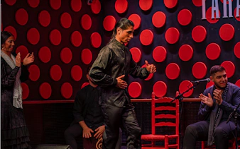 Flamenco dancer performing at Los Tarantos show in Barcelona with musicians clapping.