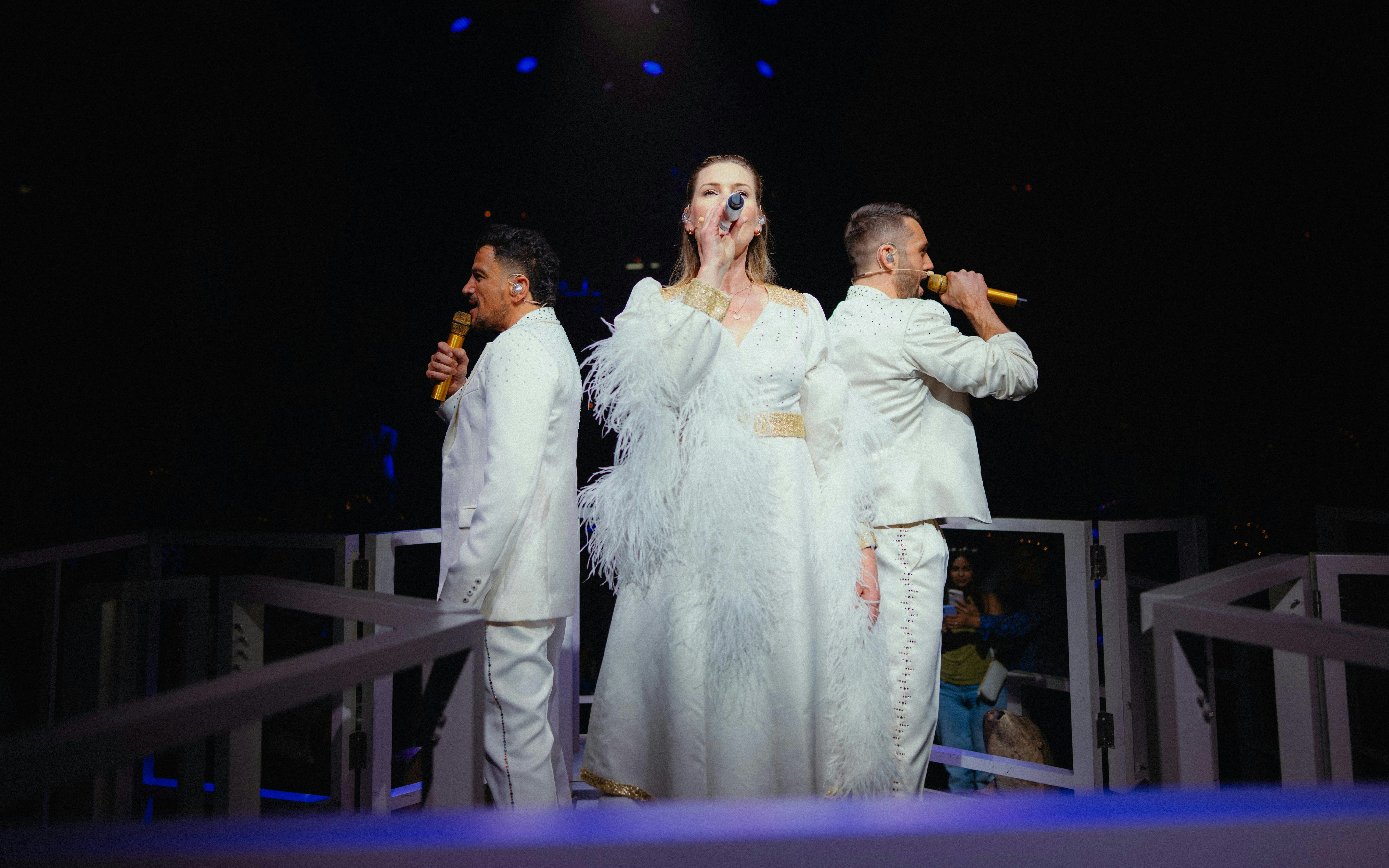 Performers singing at Mamma Mia! The Party in white costumes.