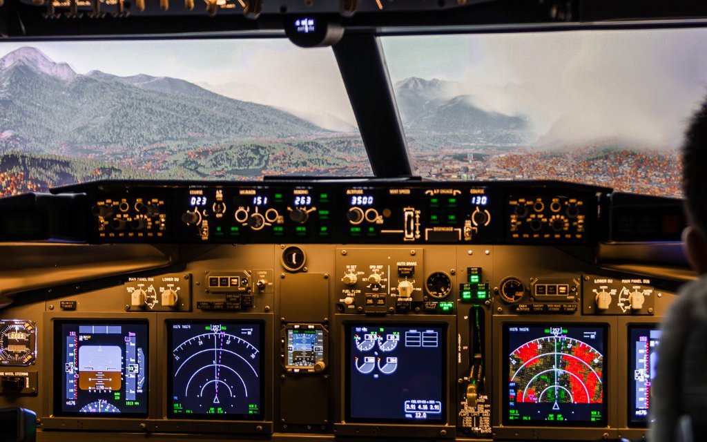 Boeing 737 cockpit view with mountainous landscape in flight simulator experience.