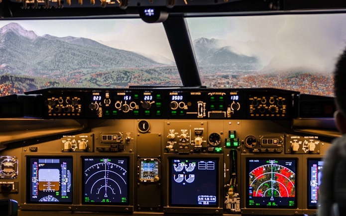 Boeing 737 cockpit view with mountainous landscape in flight simulator experience.