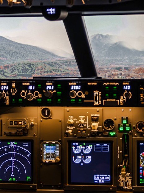 Boeing 737 cockpit view with mountainous landscape in flight simulator experience.