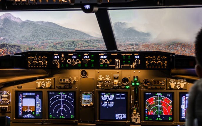 Boeing 737 cockpit view with mountainous landscape in flight simulator experience.