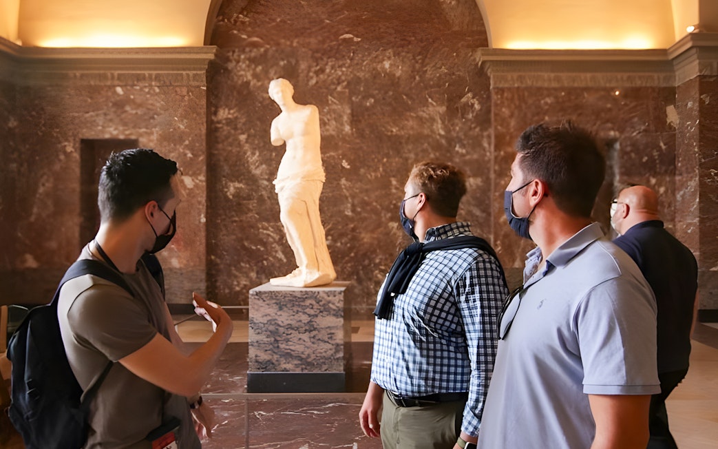 Tourists viewing the Venus de Milo statue at the Louvre Museum.