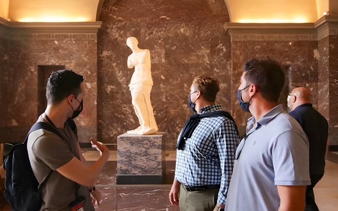Tourists viewing the Venus de Milo statue at the Louvre Museum.