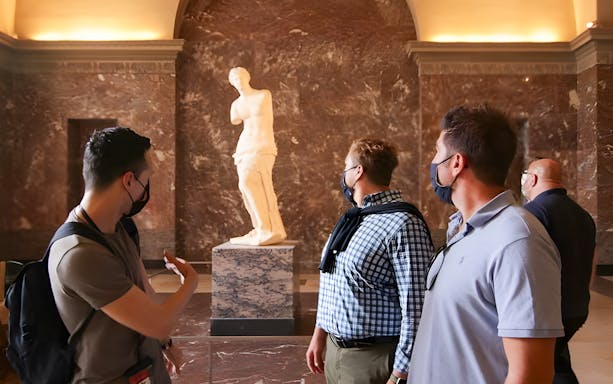 Tourists viewing the Venus de Milo statue at the Louvre Museum.