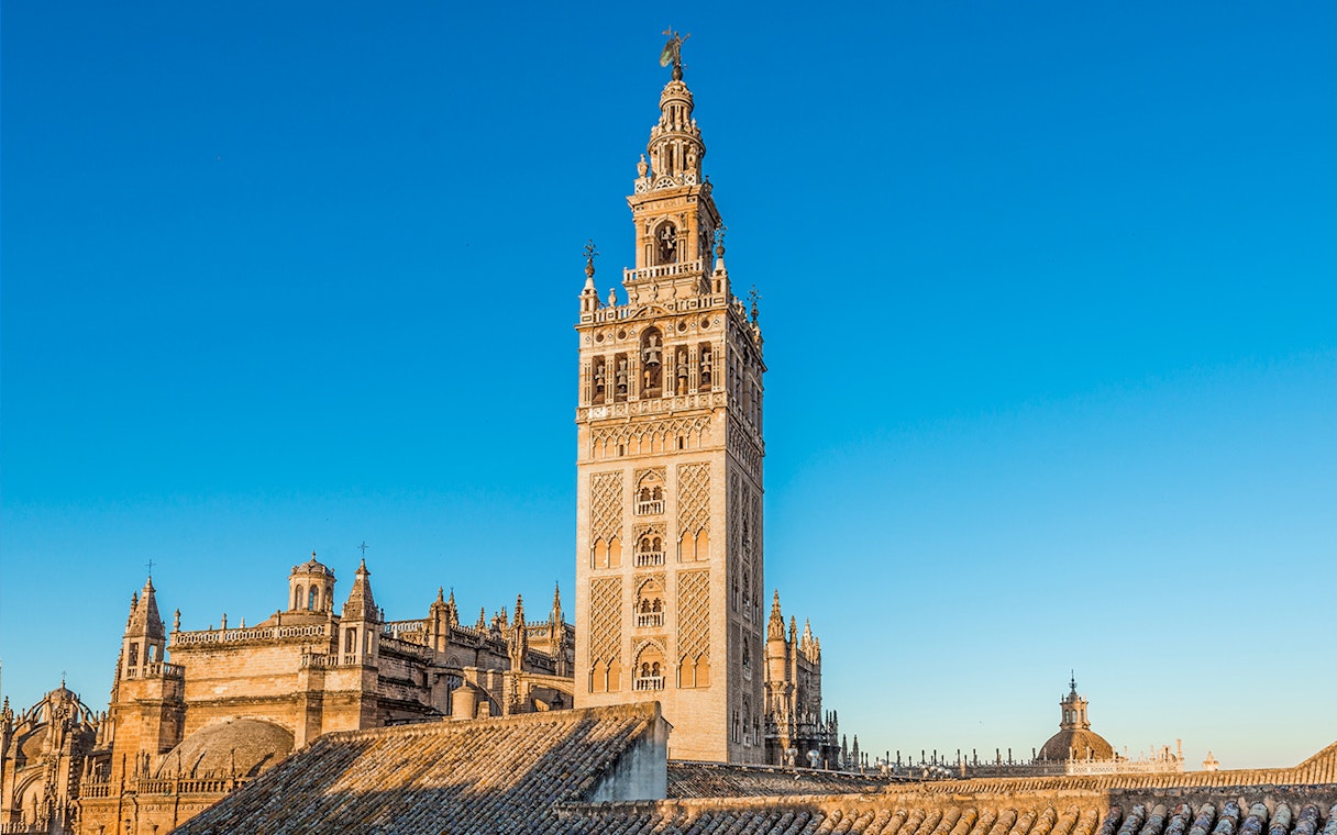Giralda tower and Seville Cathedral under clear blue sky in Seville, Spain.