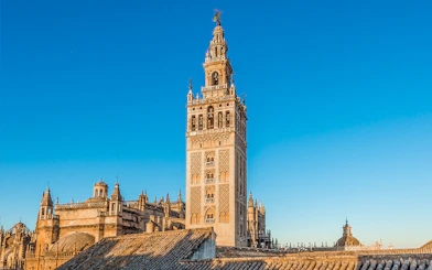 Giralda tower and Seville Cathedral under clear blue sky in Seville, Spain.