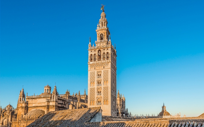 Giralda tower and Seville Cathedral under clear blue sky in Seville, Spain.