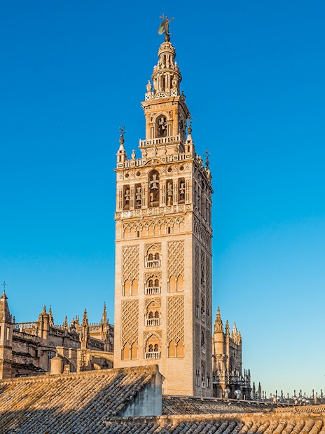 Giralda tower and Seville Cathedral under clear blue sky in Seville, Spain.