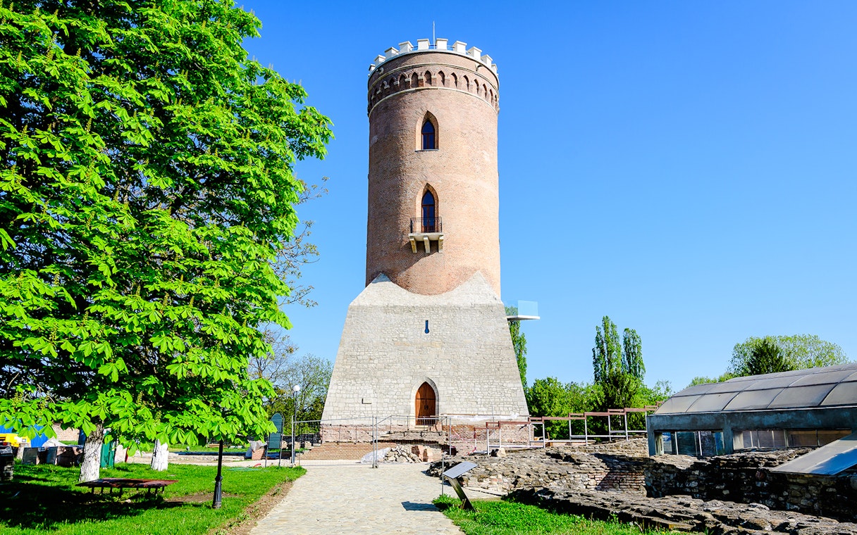 Chindia Tower in Targoviste, Romania, surrounded by greenery and historic ruins.