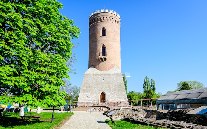 Chindia Tower in Targoviste, Romania, surrounded by greenery and historic ruins.