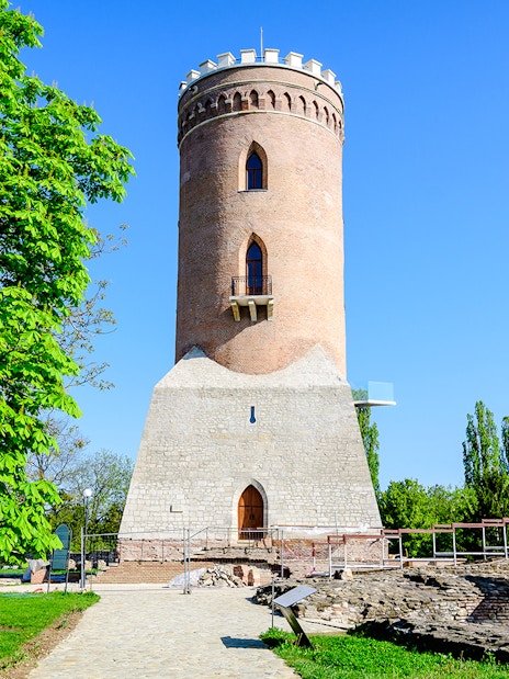 Chindia Tower in Targoviste, Romania, surrounded by greenery and historic ruins.