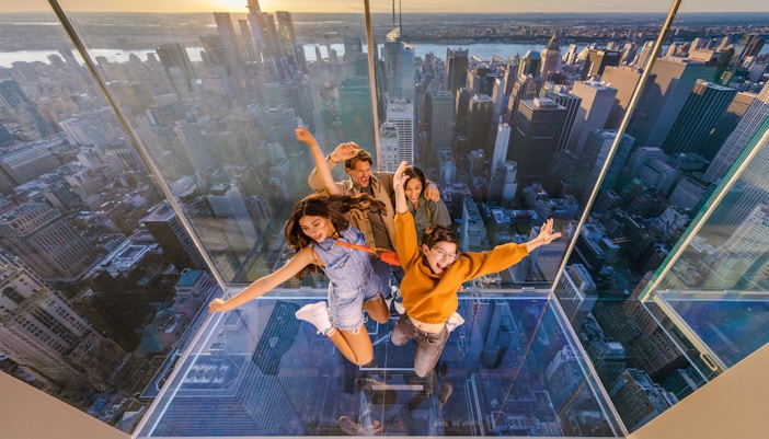 Four people on a glass platform at Summit One Vanderbilt, New York City.