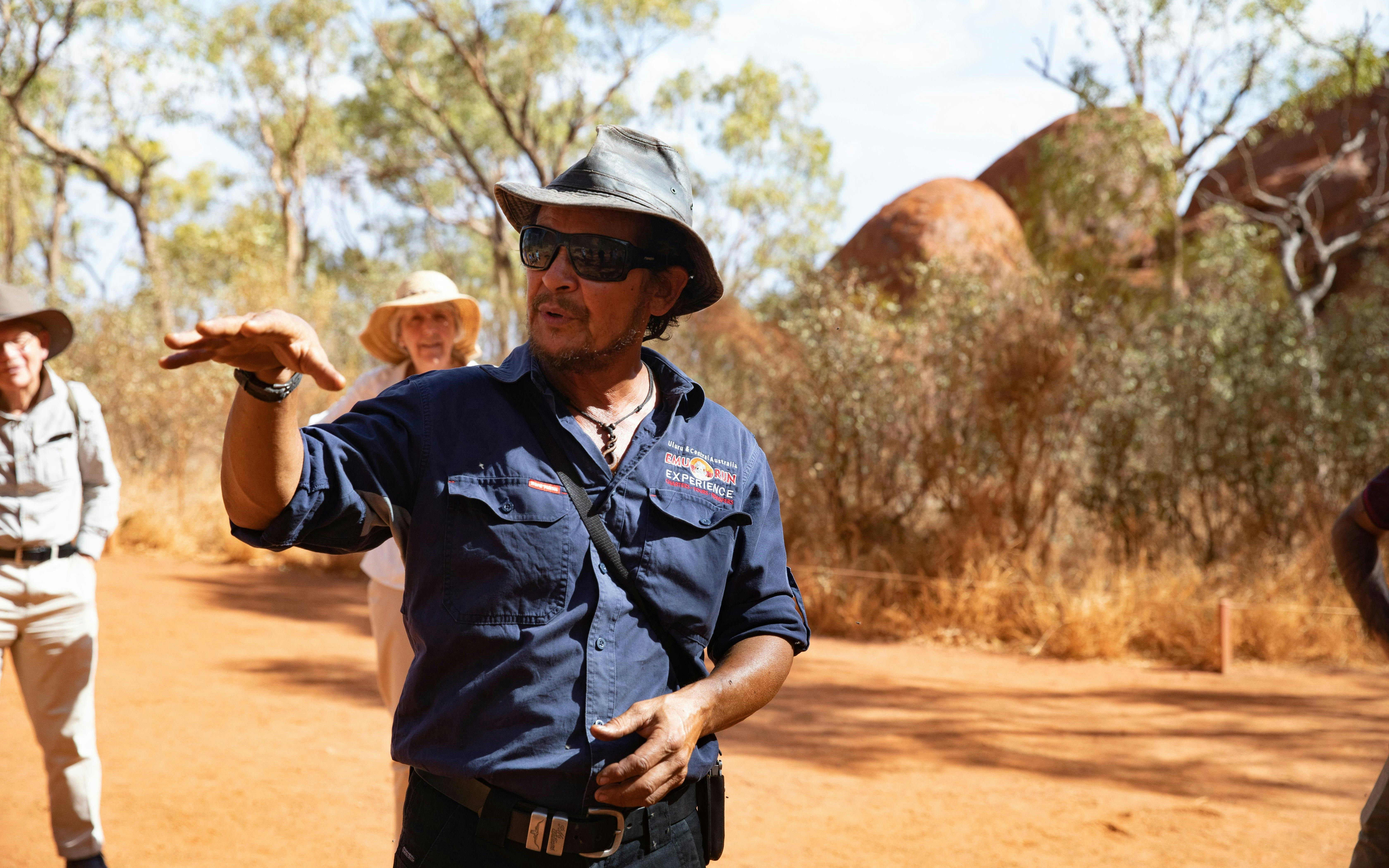 Tour guide explaining Uluru's history during a full-day tour from Alice Springs.