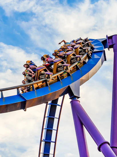Roller coaster at Six Flags Discovery Kingdom with riders on a loop against a blue sky.