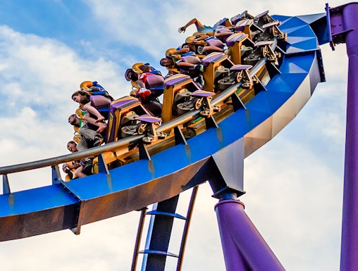 Roller coaster at Six Flags Discovery Kingdom with riders on a loop against a blue sky.